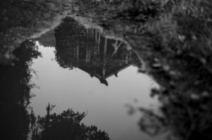 A black and white image of a building reflected in a puddle